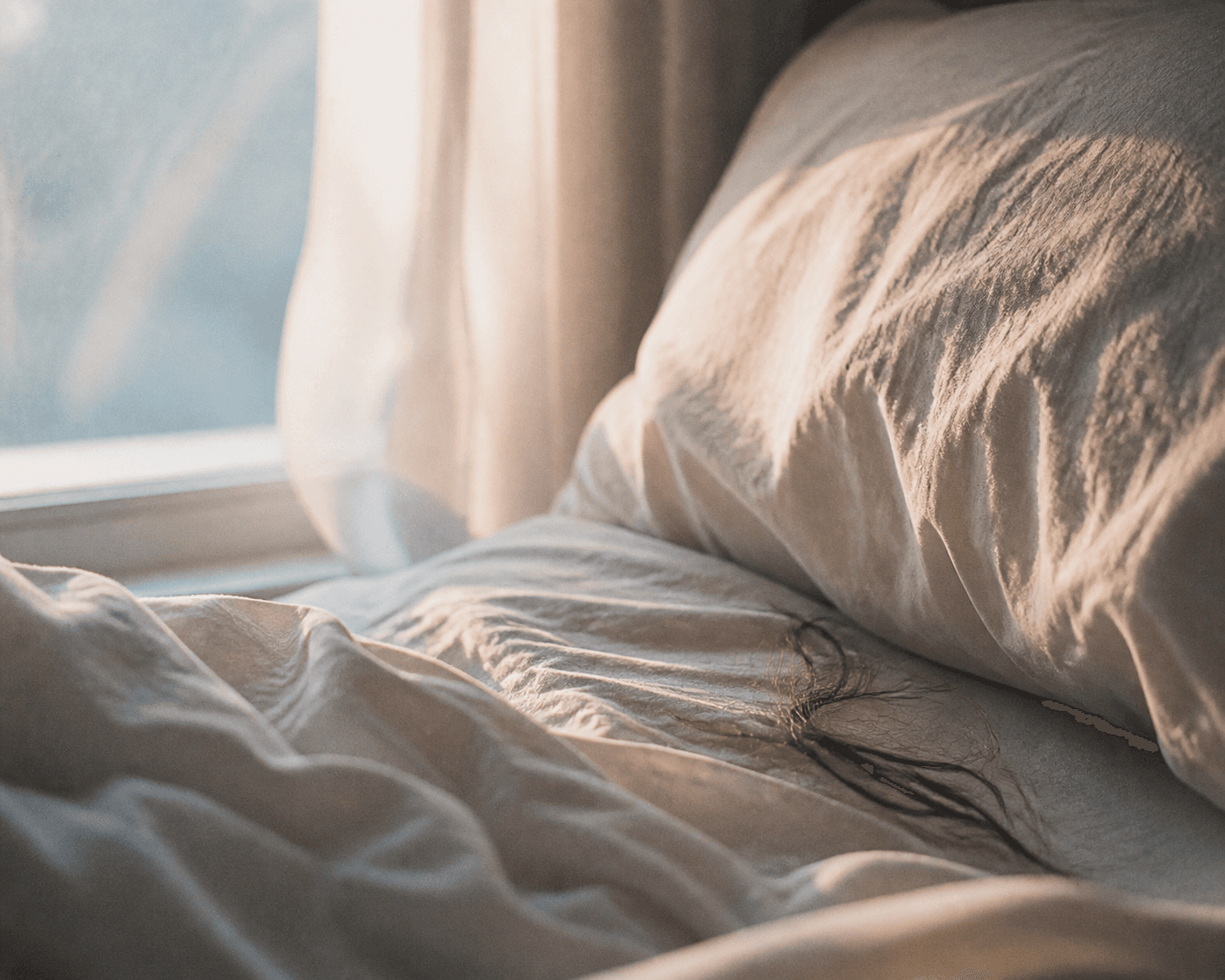 Morning light over rumpled sheets by a window