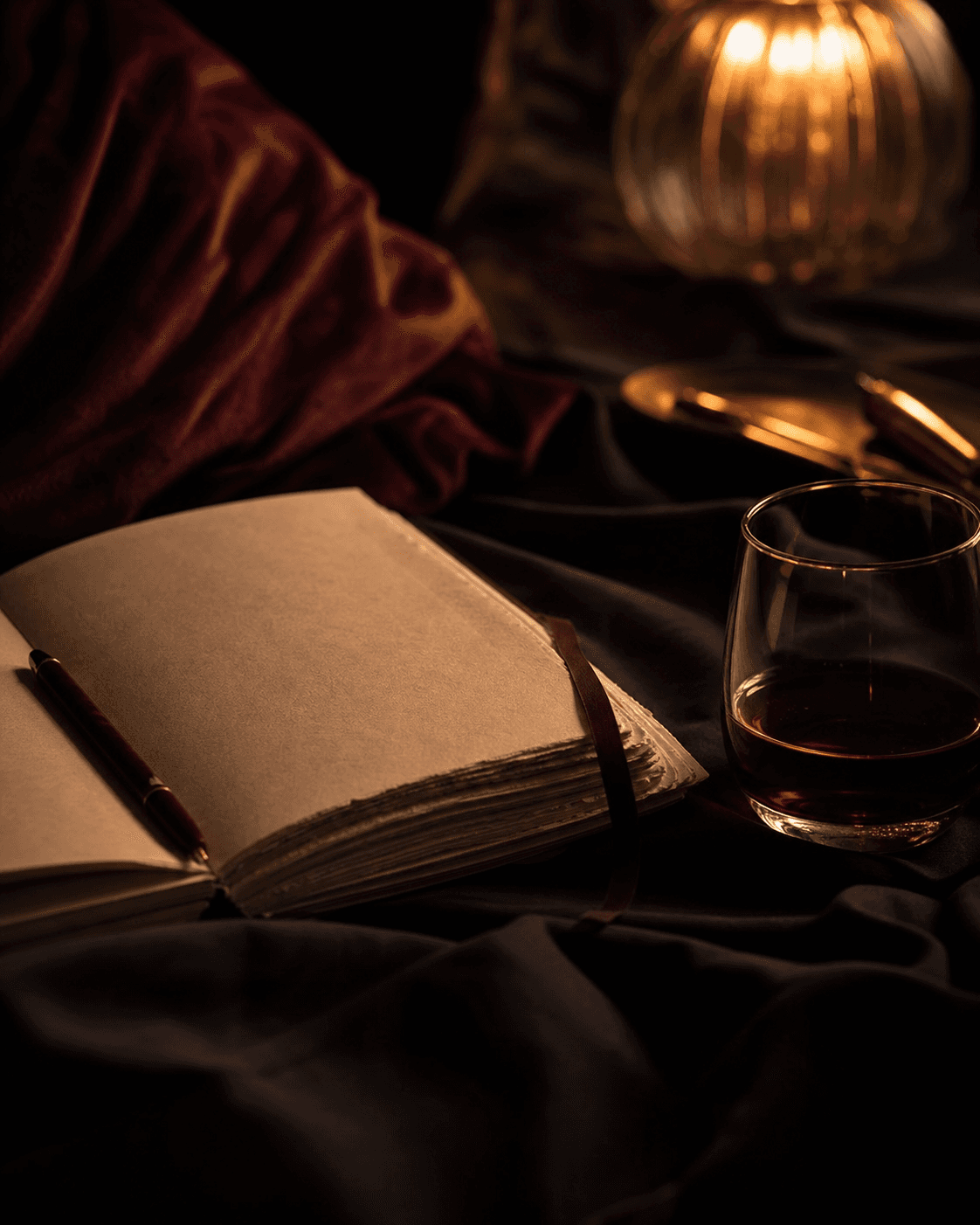 A notebook, pen, and glass in warm low light